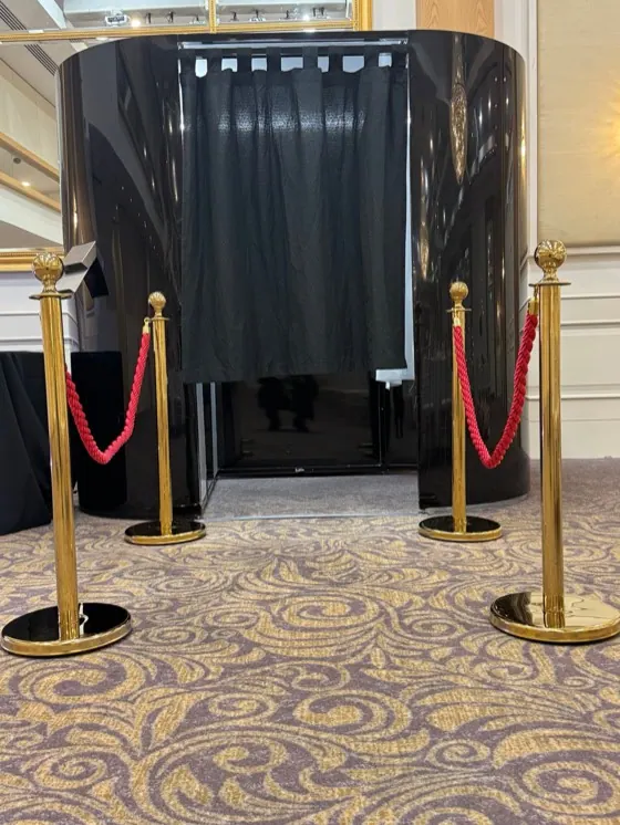 Black enclosed photo booth with gold posts and red ropes